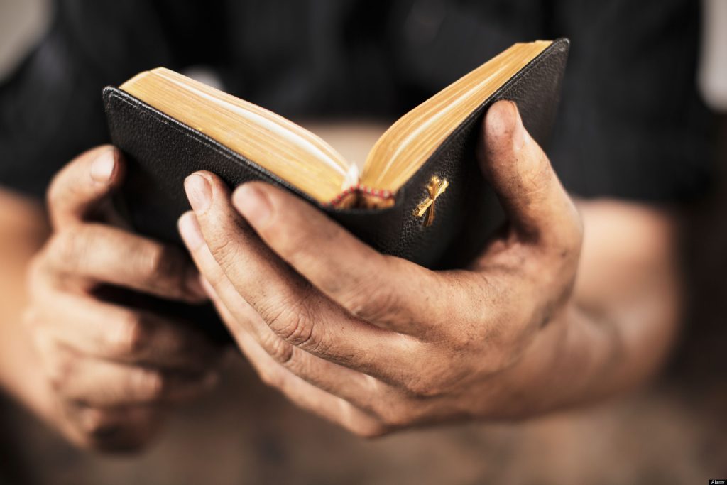 BH6KRJ Dirty hands holding an old bible. Very short depth-of-field